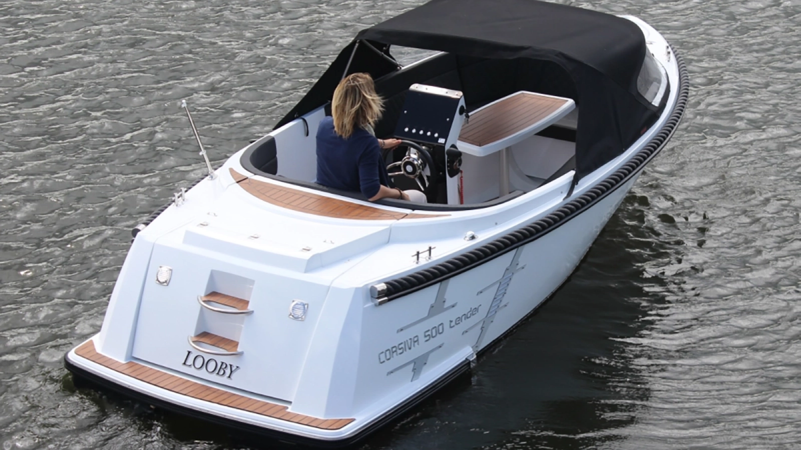 Corsiva 500 Tender Motorboot mit Verdeck auf ruhigem Gewässer, Heckansicht während der Fahrt.