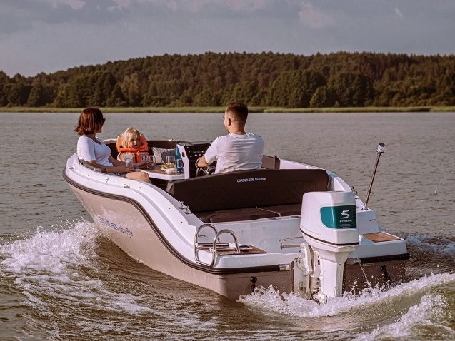 Corsiva 505 New Age mit Familie und elektrischem Außenbordmotor bei einer Fahrt auf dem See.