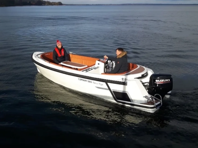 Corsiva 565 New Age mit Außenbordmotor auf ruhigem See während einer Ausfahrt mit zwei Personen an Bord.