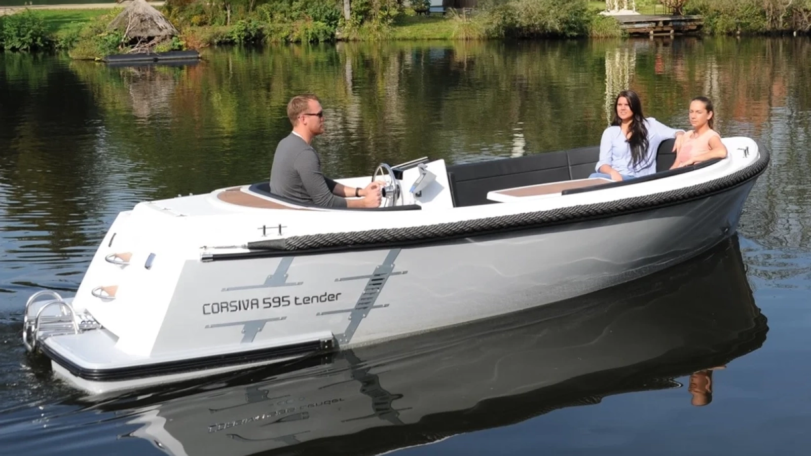 Corsiva 595 Tender mit drei Personen auf ruhigem See – modernes Motorboot mit großzügigem Cockpit, Badeplattform und Außenbordmotor.